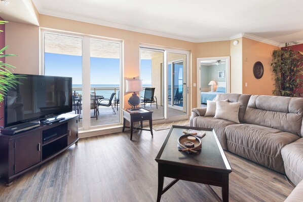 Living room off oceanfront balcony with sectional and HDTV with cable. 