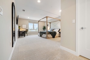 Spacious master bedroom with a king bed and a working desk.