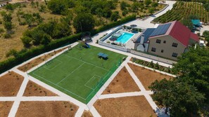 Spielbereich mit einem 21 x 18 m großen Fußballfeld mit weichem Kunstrasen und einem leicht aufzubauenden Badmintonnetz