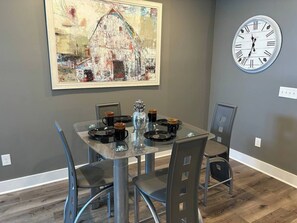 Dining Area: Stylish glass table set for culinary delights amidst vibrant artwork and chic decor.