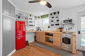 Modern Rustic Kitchen – Fully stocked with open shelving, a retro red fridge, and all the essentials.