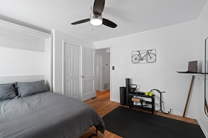 Work & Workout Bedroom – A multi-functional space with a cozy bed, workout area, and desk setup.