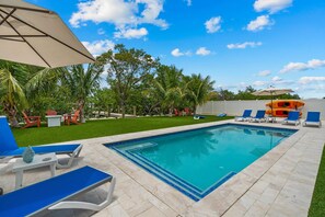 Escape to your own private oasis with this stunning house featuring a sparkling pool and cozy lawn chairs.