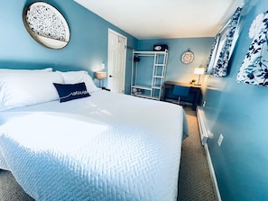 Main bedroom, queen bed, desk, clothes rack, box fan and blackout shades.