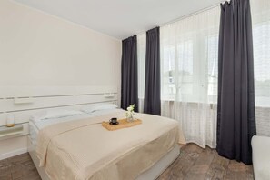 A cosy bedroom with a comfortable double bed and dark curtains hanging in the window.