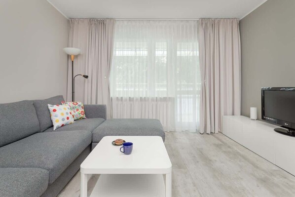 A bright living room with a grey sofa bed and a flat-screen TV for evening entertainment.