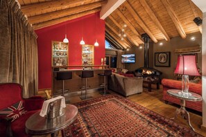 Enjoy the ambiance of this elegant living area, boasting rich red decor, a large flat-screen TV, and a vintage-inspired rug. The high wooden ceilings and ambient lighting make it an ideal spot for family gatherings and movie nights.