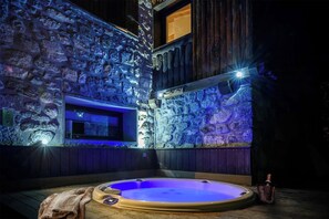 Unwind in the outdoor hot tub, set against a beautiful stone wall and illuminated by soft blue lighting. This private retreat is perfect for soaking under the stars and enjoying the tranquil sounds of nature.
