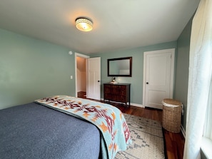 Primary bedroom has closet with hangers, hamper, dresser and two bedside tables