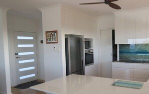 Gourmet kitchen with ceiling fans and unique splashback