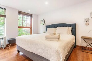 Bright white bedroom with warm wood flooring for a cozy, inviting feel.