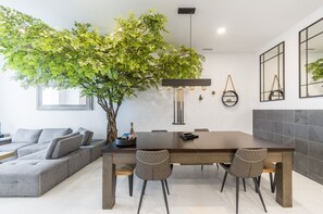 Modern dining area featuring a sleek grey table and a beautiful indoor tree for a fresh, natural touch.
