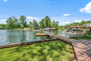 Peaceful lakefront view with a private dock and greenery.