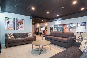 Cozy movie theater seating with grand, cinematic television and movie posters for that in theater feel! Each couch can be used for a person to sleep on.