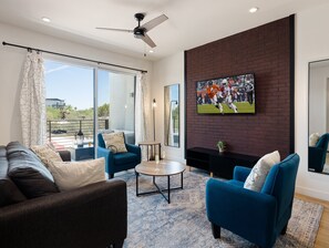 1st Floor: Warm and inviting living room featuring a Smart TV for entertainment, and designer furnishings including a sleeper sofa that converts into a Queen Bed.