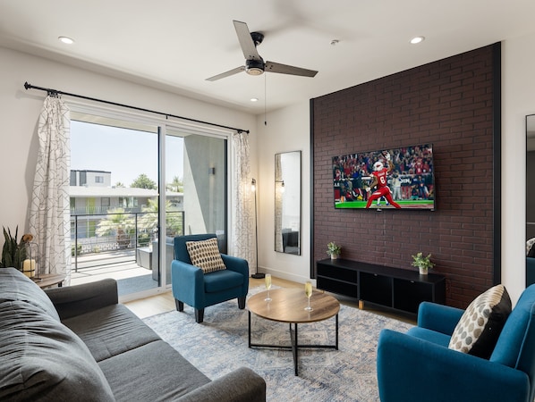 1st Floor: Warm and inviting living room featuring a Smart TV for entertainment, and designer furnishings including a sleeper sofa that converts into a Queen Bed.