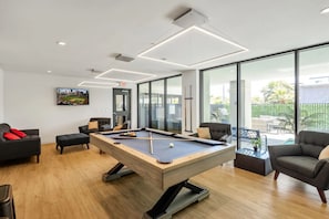 Communal Area: Pool table, lounge areas with smart TVs, communal fridge, and a half bathroom.