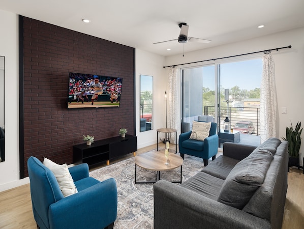 1st Floor: Warm and inviting living room featuring a Smart TV for entertainment, and designer furnishings including a sleeper sofa that converts into a Queen Bed.