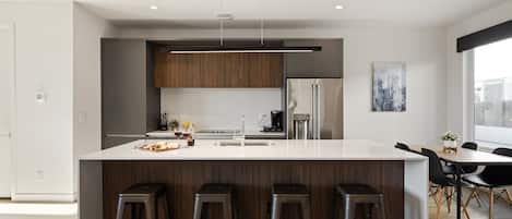 1st Floor: Fully equipped modern kitchen featuring culinary essentials, stainless steel appliances, island bar seating, and a dining area.
