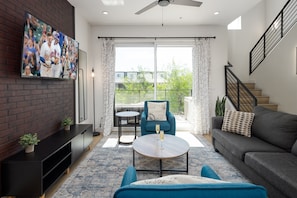 Unit 1 (1st Floor): Warm and inviting living room featuring a Smart TV for entertainment, and designer furnishings including a sleeper sofa that converts into a Queen Bed.