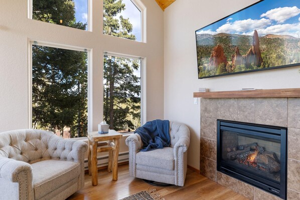 House 1 - Living room with fireplace- has two-barrel chairs, a bench and a leather couch with a recliner on each end.  It's super comfortable!