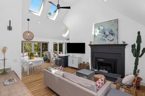 Living room and dining room with wood floors, vaulted ceilings, and fireplace