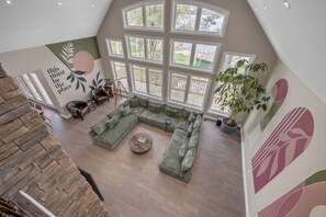 The living room is equipped with a 75-inch smart TV, panoramic views of the lake, and a large sofa.