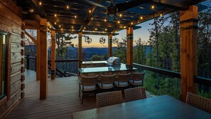 This outdoor kitchen offers a stunning mountain backdrop, complete with dining seating for eight, a gas grill, and an outdoor sink. String lights add a warm, inviting ambiance, making it the perfect setting for open air dining and entertaining.       