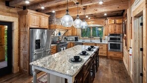 This kitchen is equipped with everything you need to prepare a meal. Just bring the food on your way into town! Large windows provide a view of the lush greenery outside, creating a warm and inviting atmosphere perfect for cooking and entertaining.