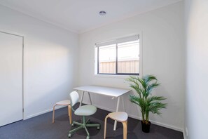 Minimalist workspace with a clean desk, chairs, and a potted plant, ideal for productivity.