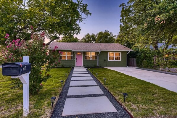 Beautiful front of the house, surrounded by lush trees and vibrant flowers, enhancing its curb appeal. The thoughtfully landscaped garden adds color and tranquility, creating a welcoming and serene atmosphere. This charming exterior combines nature’s