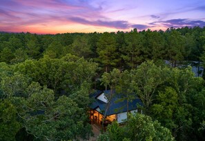 Experience the beauty of nature with this breathtaking aerial view of the property at sunset, showcasing the surrounding trees.
