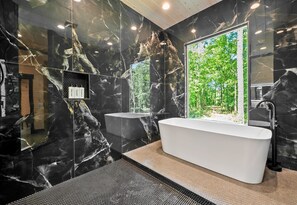 The perfect spot for relaxation, this modern bathroom features elegant black marble walls and a large picture window.