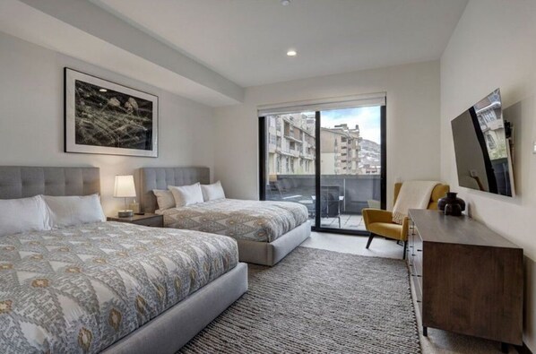 Elegant bedroom featuring two plush beds and a flat-screen TV.
