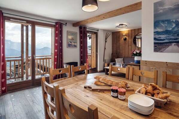 Dine with a view in the comfortable dining area, featuring rustic wooden furniture and a beautiful landscape.