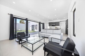 Gather with friends and family in our spacious living room, featuring a plush sofa, large TV, and an abundance of natural light, creating the perfect setting for socializing and making memories.