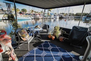 rear porch with small bistro table and two chairs for the marina ambiance. Gas barbeque grill with utensils and skewers.  Stairs to upper floor at rear of this area. Remember to come down same way you go up