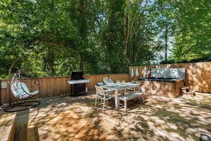 Outdoor dining, propane grill and hot tub under the trees.
