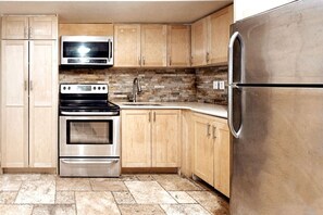 The charming kitchen where love meets flavour. Appliances and tools include: microwave, coffee maker, full-size refrigerator and freezer, cooktop and oven, pots and pans, cooking utensils, cutting board, and cutlery and dinnerware set for convenience