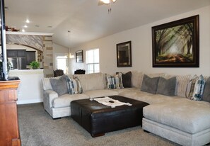 Spacious living room with a plush sectional sofa, perfect for unwinding and watching TV. The open layout flows seamlessly into the dining and kitchen areas