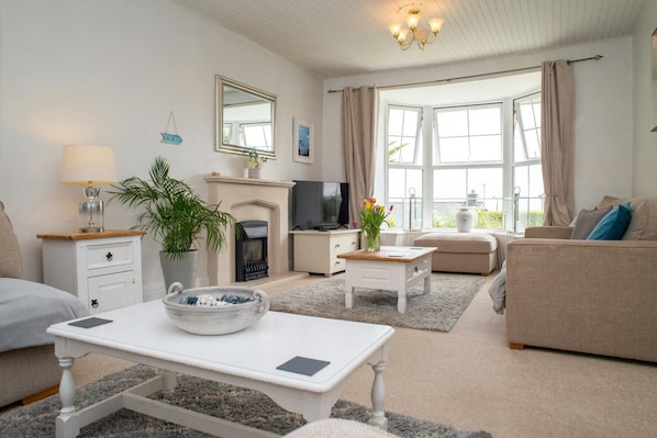 Sitting room with large bay window with distant sea views