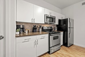 Cook with ease in this well-equipped kitchen featuring stainless steel appliances, ample cabinetry, and a stylish backsplash. Whether you're brewing coffee or preparing a gourmet meal, this space is designed for functionality and style, making every meal