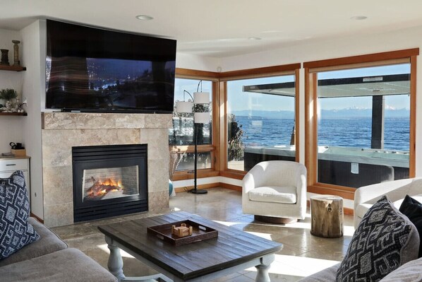 Our beachfront living room offers panoramic views of Whidbey Island's pristine waters, inviting you to unwind in style. Sink into plush furnishings amidst coastal charm, where every detail reflects relaxation and luxury.
