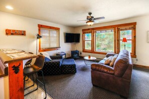 The cozy living room features comfortable seating, a stone fireplace, and rustic décor, creating the perfect atmosphere for unwinding after a day of outdoor adventures in Grand Lake.

