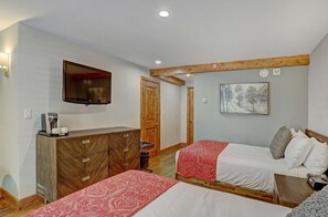 Relax in the comfort of this well-appointed bedroom, featuring a plush bed with premium linens, a wall-mounted TV, and ample storage space. 