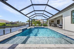Spacious screened pool area with plenty of seating and a serene canal backdrop.