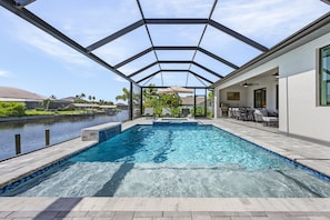Spacious screened pool area with plenty of seating and a serene canal backdrop.