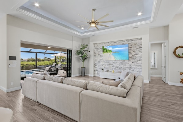 Bright, airy living room with cozy seating and large TV, perfect for relaxation.