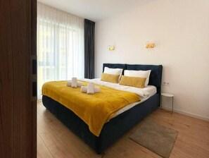 Stylish bedroom equipped with large bed with soft linens, fluffy pillows, freshly cleaned towels, room-darkening shades and beside table