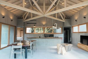 The living room has a large roof with impressive exposed beams. This extremely minimalist space changes its appearance depending on the light that shines in.